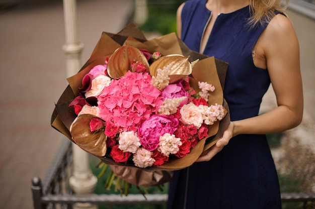 Mädchen, das Blumenstrauß der rosa Blumen hält, verziert mit Goldblättern