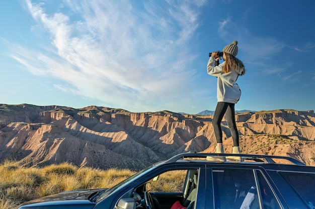 Mädchen, das die Wüstenlandschaft beobachtete, kletterte auf das Dach eines Offroad-Trucks