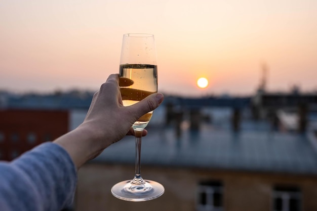 Mädchen, das ein Glas Champagner in den Sonnenuntergang hält