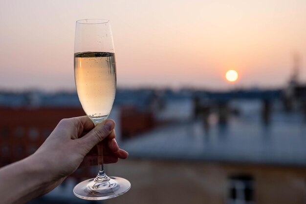 Mädchen, das ein Glas Champagner in den Sonnenuntergang hält