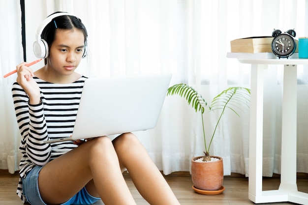 Mädchen, das ein Headset trägt und während der häuslichen Quarantäne zu Hause online lernt.