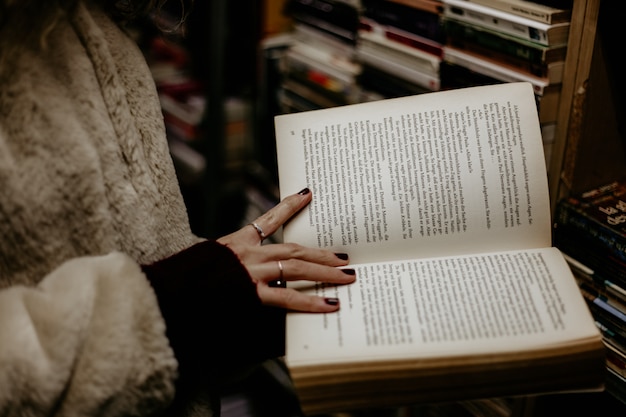 Mädchen, das ein offenes Buch in ihren Händen im Buchladen hält.