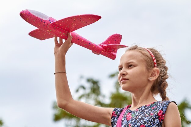 Mädchen, das ein rosa Spielzeugflugzeug in die Luft startet