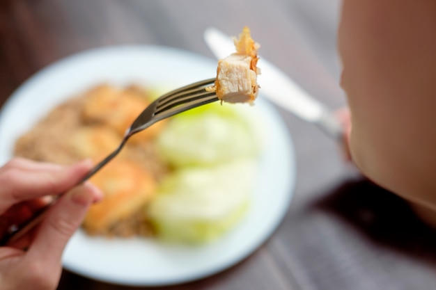 Mädchen, das ein Stück Huhn mit Gabel isst