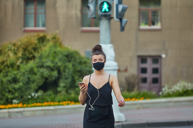 Mädchen, das eine Gesichtsmaske trägt, die die Straße kreuzt