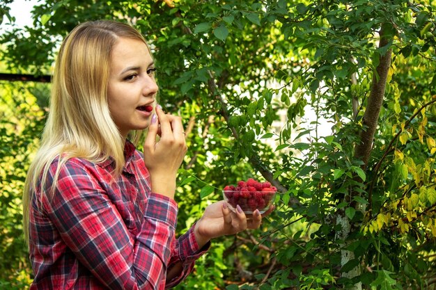 Mädchen, das eine schüssel mit bio-produkt von reifen himbeeren auf dem bauernhof hält.