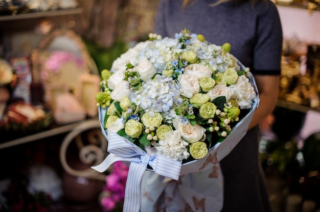 Mädchen, das einen Blumenstrauß der weißen und grünen Ranunkeln und der blauen Hortensien hält