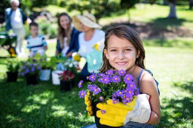 Mädchen, das einen Blumentopf bei der Gartenarbeit mit Familie hält