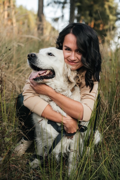 Mädchen, das einen golden retriever-hund auf dem feld umarmt