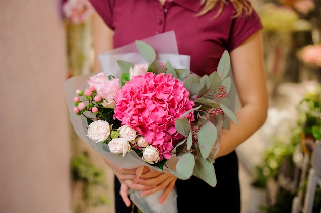Mädchen, das einen stilvollen Blumenstrauß von rosa Rosen, Hortensie, Eukalyptus hält