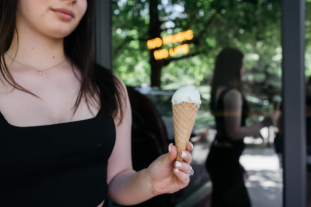 Mädchen, das Eis in ihren Händen auf einem Hintergrund des Körpers hält Mädchen, das Eis in ihren Händen hält Leckeres Eis im Sommer Sommer und Hitze