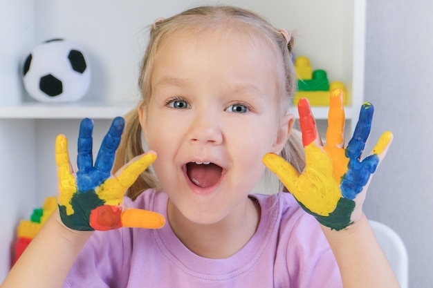 Mädchen, das gemalte Hände zeigt. Hände in bunten Farben gemalt.