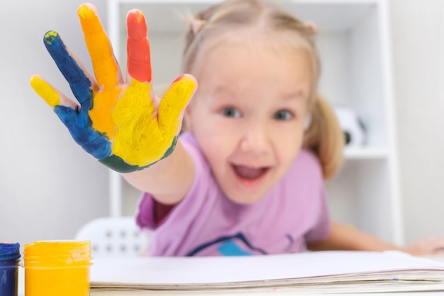 Mädchen, das gemalte Hände zeigt. Hände in bunten Farben gemalt