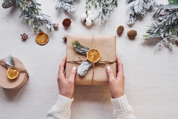 Mädchen, das Geschenkbox macht. Draufsicht des festlichen Weihnachtsrahmens mit Dekorationen des neuen Jahres.