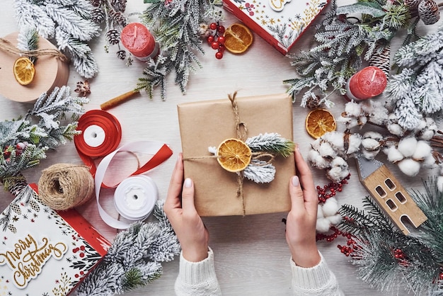 Mädchen, das Geschenkbox macht. Draufsicht des festlichen Weihnachtsrahmens mit Dekorationen des neuen Jahres.