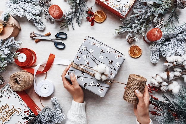 Mädchen, das Geschenkbox macht. Draufsicht des festlichen Weihnachtsrahmens mit Dekorationen des neuen Jahres.