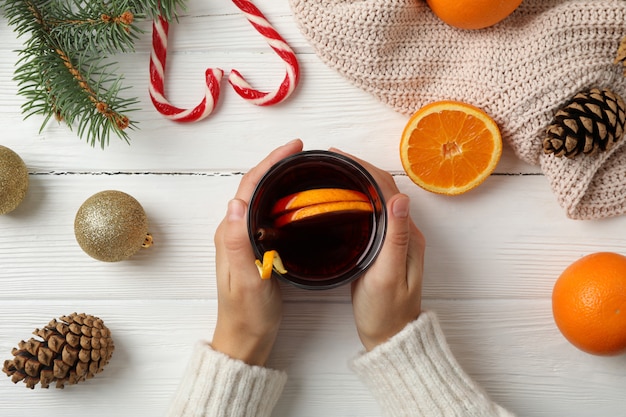 Mädchen, das Glas mit Glühwein auf verziertem Holztisch, Draufsicht hält