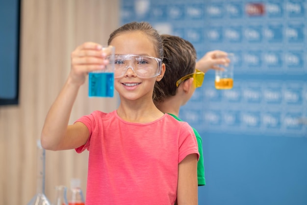 Mädchen, das Glas zeigt, das in die Kamera schaut