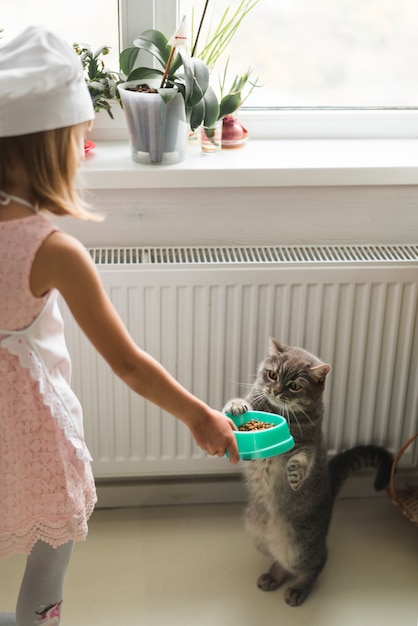 Mädchen, das ihrer Katze Nahrung gibt