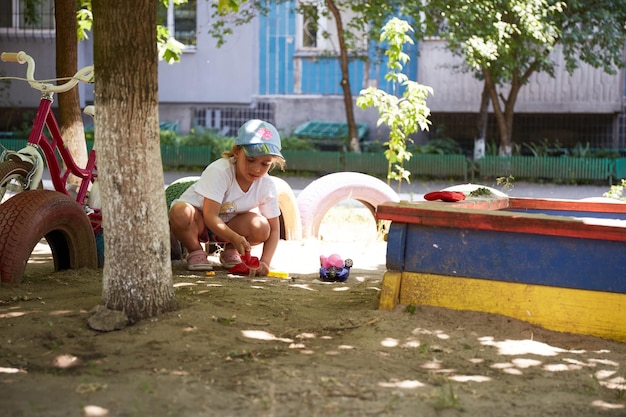 Mädchen, das im Hof mit Sand spielt Realistisches Kinderporträt