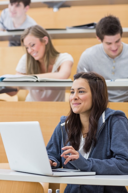 Mädchen, das im Vorlesungssal unter Verwendung des Laptops sitzt