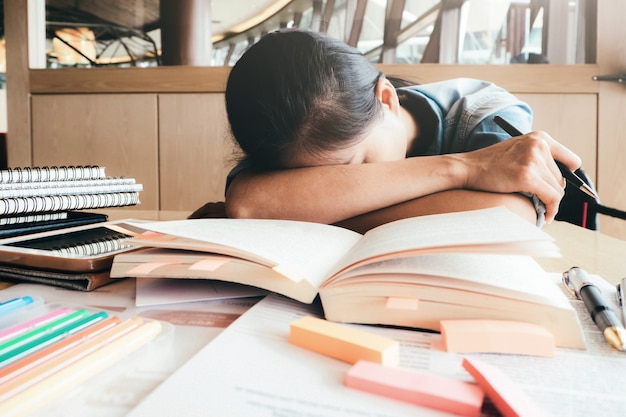 Mädchen, das in der Bibliothek hart liest und schläft.