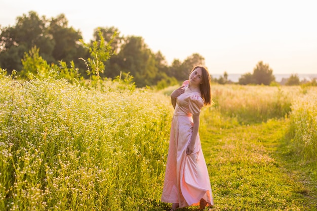 Mädchen, das in einem rosa Kleid auf dem Feld steht