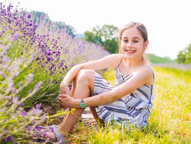 Mädchen, das in einem violetten Lavendelfeld sitzt