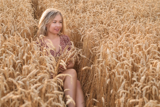 Mädchen, das in einem Weizenfeld sitzt und lächelt