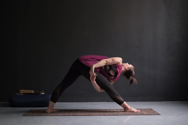 Mädchen, das in Utthita Trikonasana erweiterter Dreieckhaltung steht