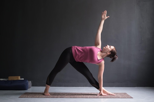 Mädchen, das in Utthita Trikonasana erweiterter Dreieckhaltung steht