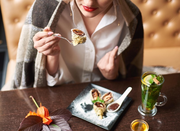 Mädchen, das leckere süße Sushi-Rolle mit Schokoladensauce isst.