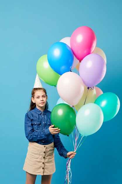 Mädchen, das Luftballons auf Blau hält