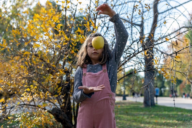 Mädchen, das mit Apfel nahe Busch spielt