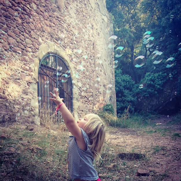 Foto mädchen, das mit blasen auf dem feld spielt