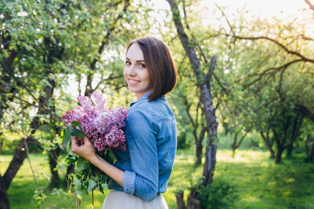 Mädchen, das mit einem Blumenstrauß von Flieder aufwirft