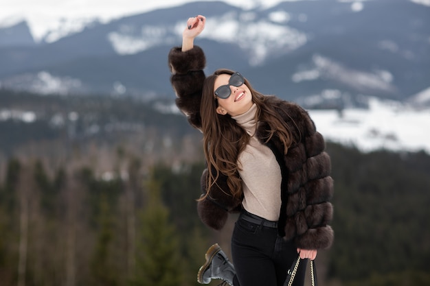 Mädchen, das mit erhöhtem Arm auf Winterbergen aufwirft