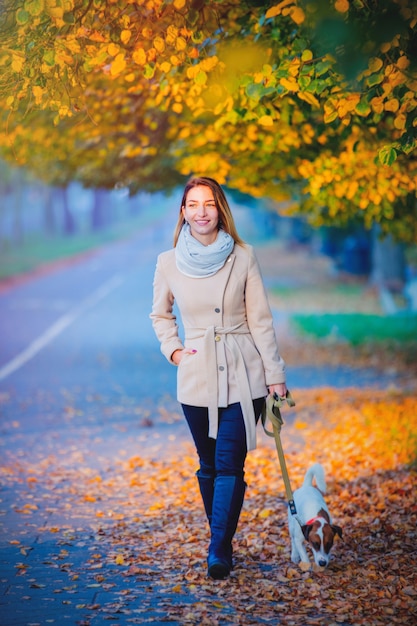 Mädchen, das mit Hund an der Herbstsaisongasse geht