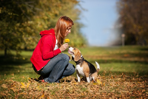 Mädchen, das mit ihrem Hund im Herbstpark spielt