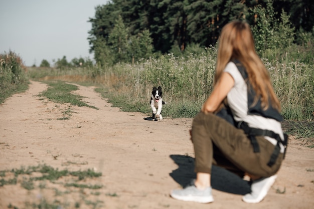 Mädchen, das mit Schwarzweiss-Randcollie-Hundewelpe auf dem Waldweg spielt