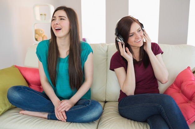 Mädchen, das Musik mit ihrem Freund neben ihr auf dem Sofa hört