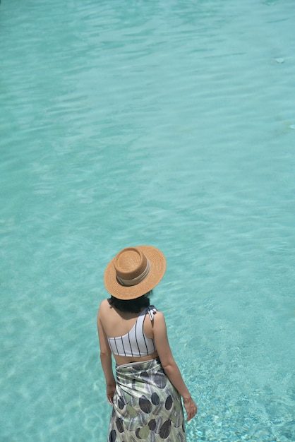 Mädchen, das nahe am Pool in einem modischen Badeanzug mit Pool aufwirft, reflektiert im Hintergrund / Sommeraktivität
