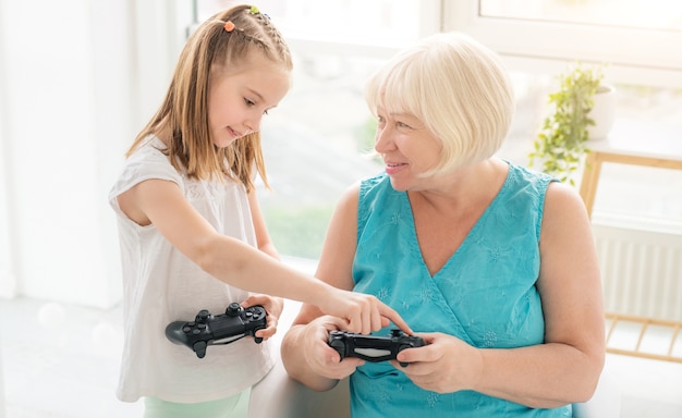 Mädchen, das Oma lehrt, auf Joystick zu spielen