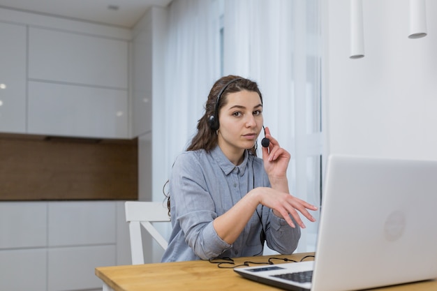 Mädchen, das online mit Laptop unter Verwendung des Headsets arbeitet