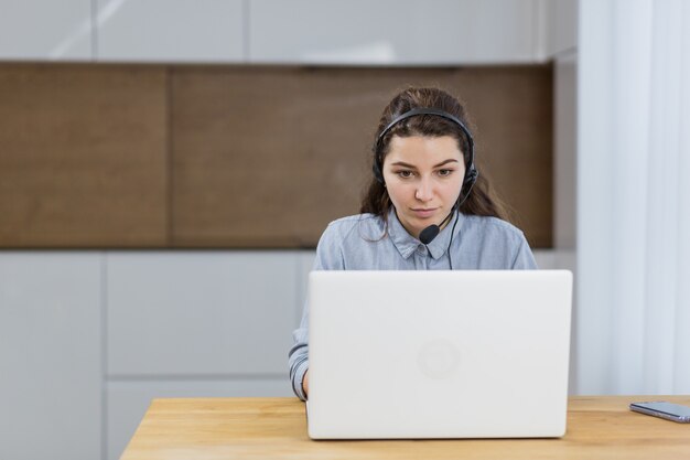 Mädchen, das online mit Laptop unter Verwendung des Headsets arbeitet