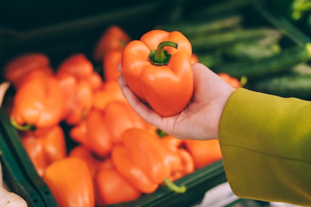 Mädchen, das Paprika in ihrer Hand in einem Supermarkt hält.