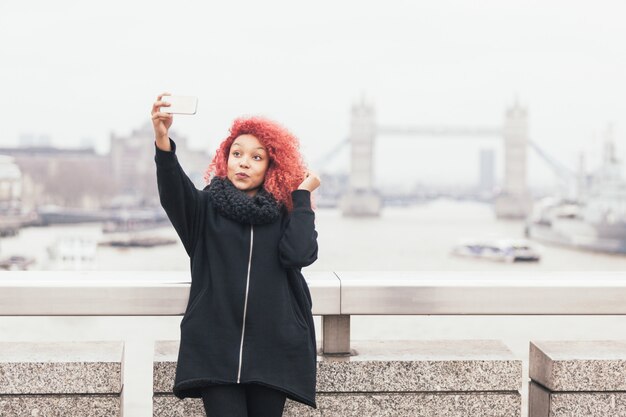 Mädchen, das selfie in London mit Tower Bridge nimmt