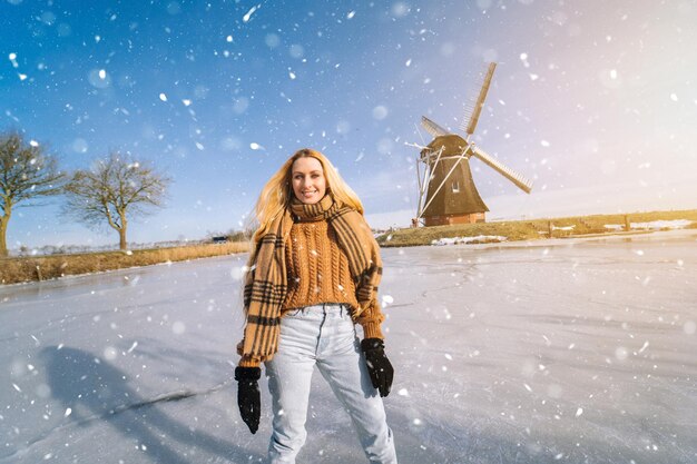 Mädchen, das Spaß auf dem Eis in typisch holländischer Landschaft mit Windmühlenfrau hat, die auf Eisbahn draußen eislaufen?