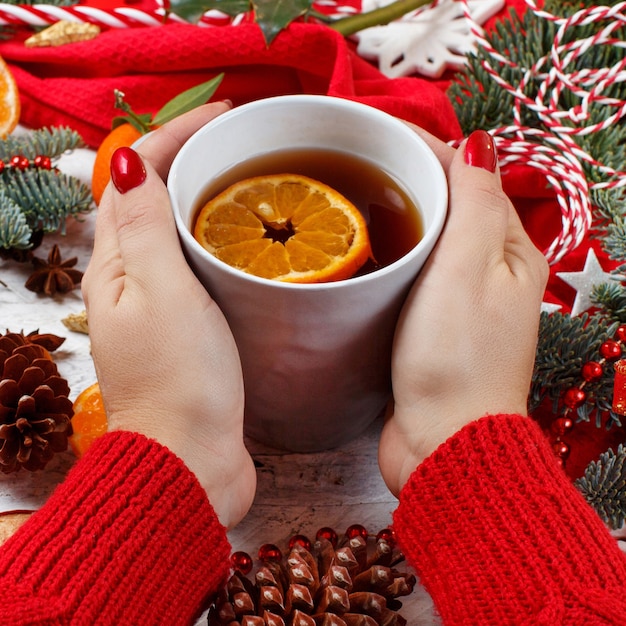 Mädchen, das Teebecher mit Weihnachten mit Dekorationen und Tannenzweigen herum hält