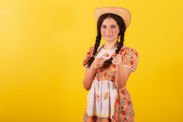 Mädchen, das traditionelle orangefarbene Kleidung für festa junina trägt Zeigefinger, die dich ausgewählt haben